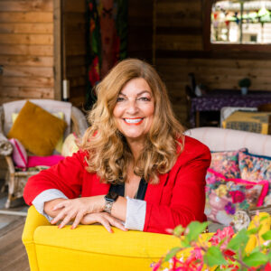 Sandra Garlick MBE Sitting on a yellow chair